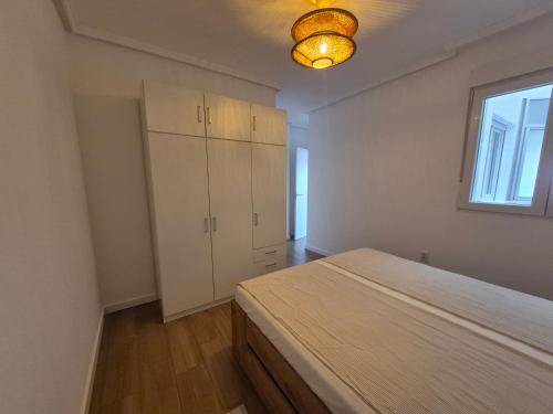 an empty bedroom with a bed and a window at Playa Los Náufragos Torrevieja in Torrevieja
