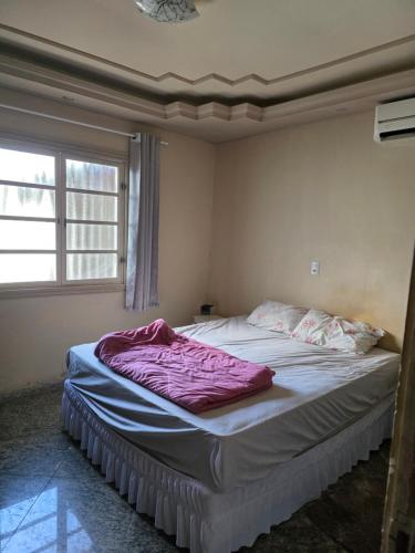 a bedroom with a bed with purple sheets and a window at momento de paz in Sumaré