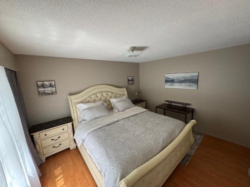 a bedroom with a large bed and a wooden floor at Cozy nest in Coquitlam