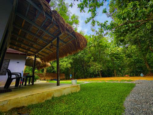 a hut with a grass roof and a table and chairs at EMERALD HAVEN Safari Glamping in Udawalawe