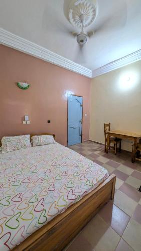 a bedroom with a large bed and a table at Hôtel St Jo in Bohicon