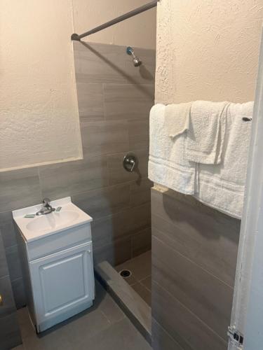 a bathroom with a sink and a shower with towels at Terrace Motel in Natchez