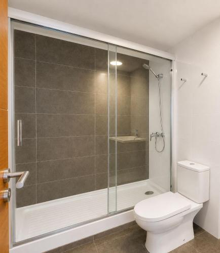 a bathroom with a toilet and a glass shower at Distrito Cavancha in Iquique