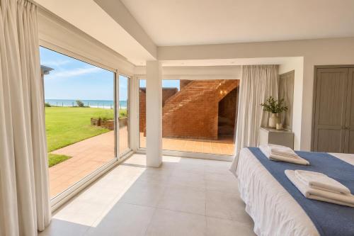 a bedroom with a bed and a large glass window at Despertá frente al mar! Loft con bajada privada! in Santa Clara del Mar