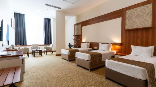 a hotel room with two beds and a sitting area at Kule Hotel&Spa Gaziantep in Şahinbey