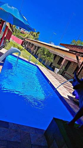 a large blue swimming pool next to a house with an umbrella at Pousada Açaí in Salvaterra