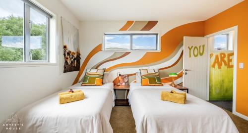 two beds in a room with orange walls at The Artist's House Wanaka in Luggate