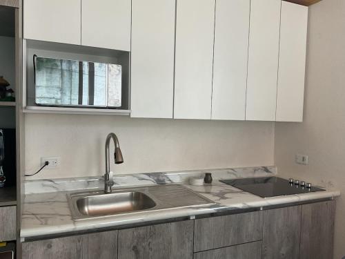 a kitchen with a sink and white cabinets at Cabaña, fogata, terraza in Santiago Sacatepéquez