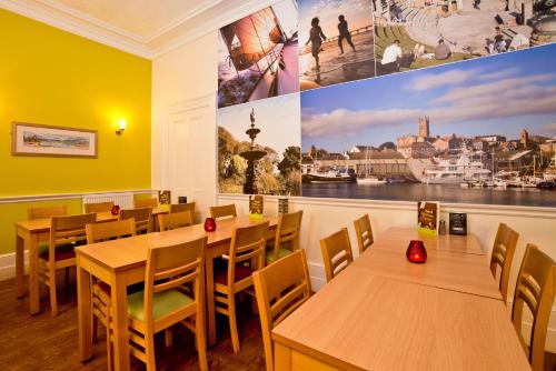 a restaurant with tables and chairs and a large painting on the wall at YHA Penzance in Penzance
