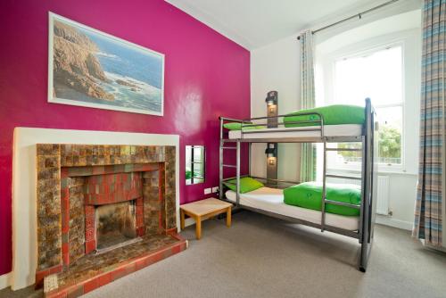 a bedroom with two bunk beds and a fireplace at YHA Penzance in Penzance