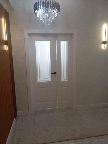 a hallway with a white door and a chandelier at happy home in Bishkek