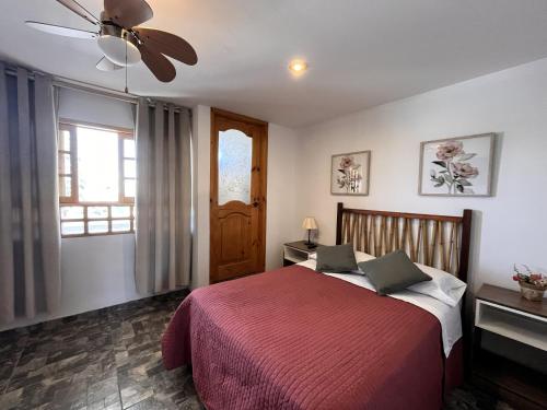 a bedroom with a red bed and a ceiling fan at El Huerto Hostel in Ica