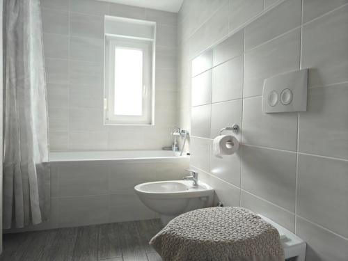 a white bathroom with a toilet and a bath tub at Apartments Miraflor, city center in Crikvenica