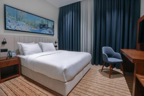 a hotel room with a large bed and a desk at Jizzax Hotel Tashkent in Tashkent