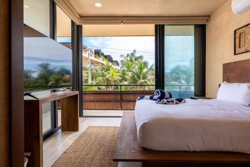 a bedroom with a large bed and a large window at BT Homes - Tankah Bay Tulum - Exclusivos apartamentos con piscina a metros del mar in Tancah