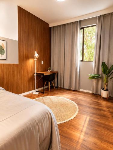 a bedroom with a bed and a desk and a window at Apartamento Premium Centro 103 in Foz do Iguaçu