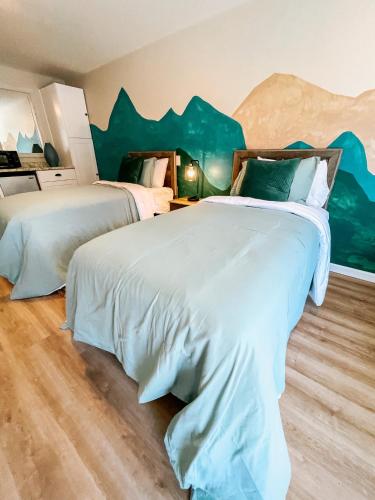 two beds in a room with a mountain mural on the wall at Meadow Room at The Trailblazer Unit 12 in Townsend