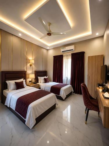 a hotel room with two beds and a desk at Hotel Regent DHA in Karachi