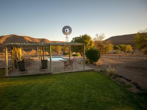 a gazebo with a table and chairs and a windmill at Zebra River Lodge in Maltahöhe