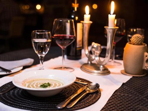 a table with a bowl of soup and glasses of wine at Zebra River Lodge in Maltahöhe