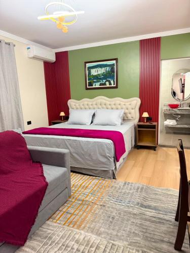 a bedroom with a large bed and a couch at Pousada Lumiera House in Foz do Iguaçu