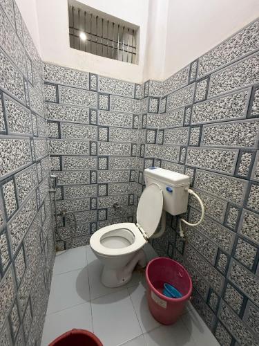 a bathroom with a toilet and a red bucket at Shri Raghuveer guest house in Ayodhya