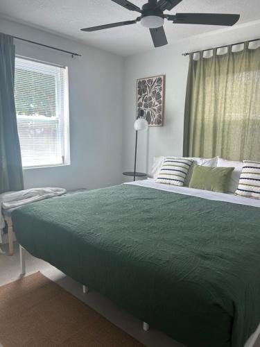 a bedroom with a green bed with a ceiling fan at cozy bohemian in North Miami