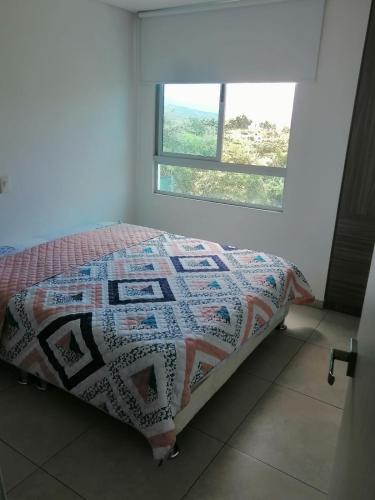 a bed with a quilt on it in a room with a window at Modern apartment with pool-La Mesa in La Mesa