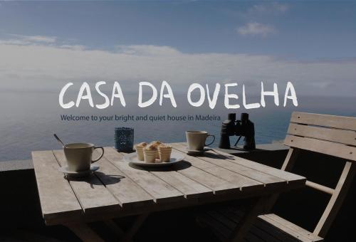 a wooden table with two cups and cookies on it at Casa da Ovelha I Madeira in Fajã da Ovelha