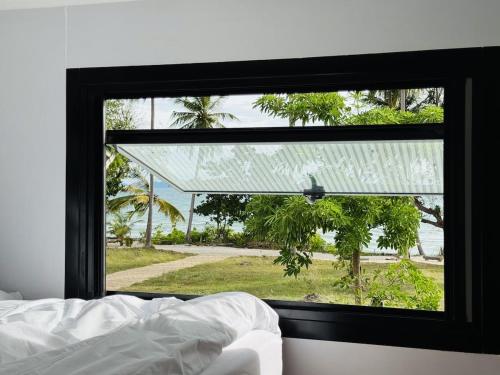 a bedroom window with a view of a yard at Private Sunset Beachfront Thainee Villa in Nathon Bay