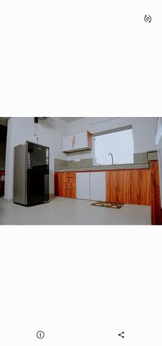 a kitchen with white cabinets and a black refrigerator at Corniche inn river view villa 2 BHK in Kāsaragod