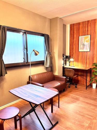a living room with a couch and a table at Osaka Petite Tanuki Inn Neyagawa in Neyagawa