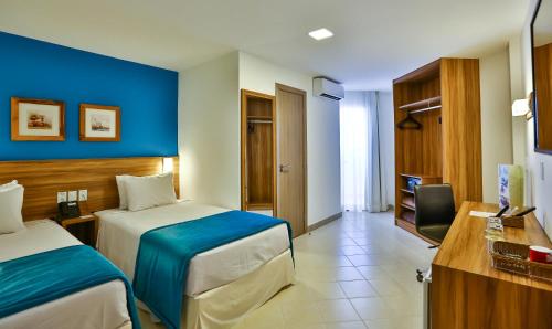 a hotel room with two beds and a blue wall at ARCUS Hotel By Atlântica in Aracaju
