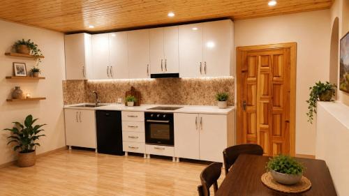 a kitchen with white cabinets and a table with chairs at Teo Guesthouse and Camping in Mestia in Mestia