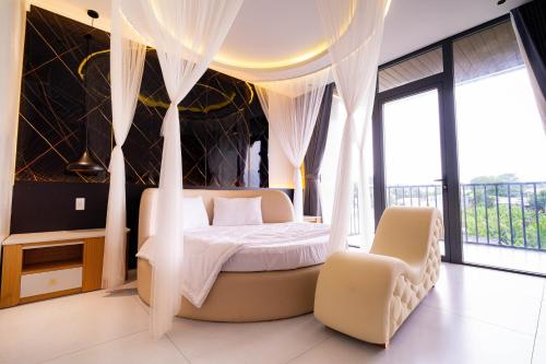 a bedroom with a bed with curtains and a chair at Mia Hotel in Ga Trảng Bôm