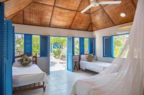 a bedroom with two beds and blue shuttered windows at Bayside Island in Cartagena de Indias