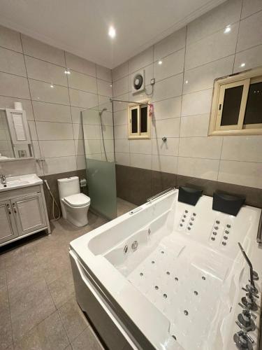 a large bathroom with a tub and a toilet at شقق البيلسان الذهبي للشقق المخدومة in Jeddah