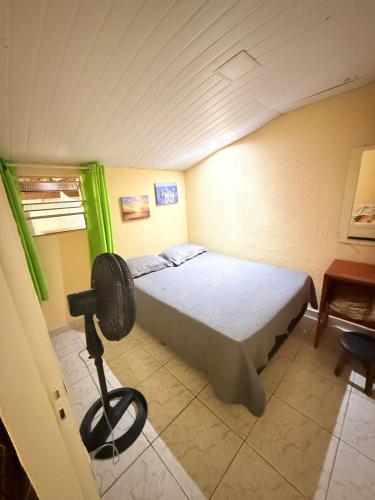 a bedroom with a bed with a fan in it at Casa baixinha in Ubajara