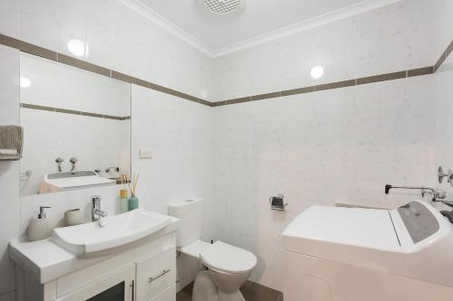 a white bathroom with a toilet and a sink at Viewpoint in Tathra