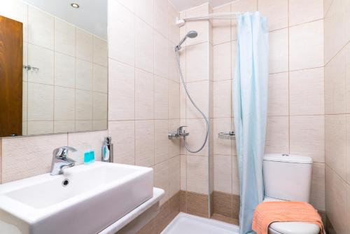 uma casa de banho com um lavatório, um chuveiro e um WC. em Hotel Olympion em Potos