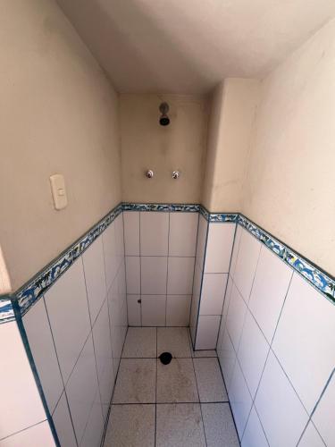a room with white tiled showers with a spotlight at Kusikuy Wasy Lodge in Puno