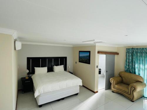 a bedroom with a bed and a chair at RS GARDEN GUESTHOUSE in Thohoyandou