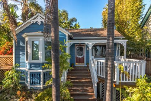 a blue house with palm trees in front of it at Lillie by the Sea in Summerland