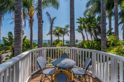 a balcony with chairs and palm trees and the ocean at Lillie by the Sea in Summerland