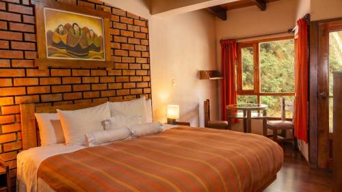 a bedroom with a bed and a brick wall at Andina Principal in Machu Picchu