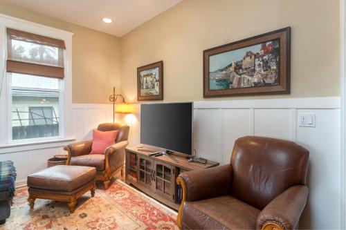 a living room with two chairs and a flat screen tv at Magnolia Cottage in Santa Barbara