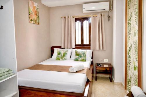 a bedroom with a bed with white sheets and green pillows at Hotel Lua Origenes Rodadero, Santa Marta in Santa Marta