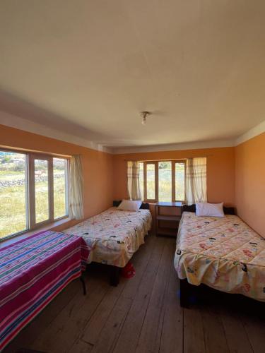 two beds in a room with windows at Kusikuy Wasy Lodge in Puno