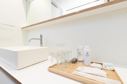 a bathroom counter with a sink and glasses on a tray at Takeno-an in Mitaka