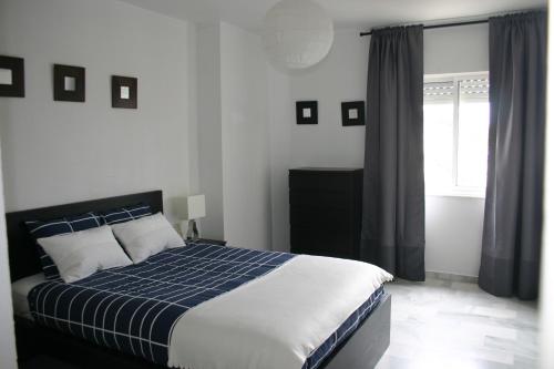 Un dormitorio con una cama azul y blanca y una ventana en Apartamento Las Adelfas, en Jerez de la Frontera